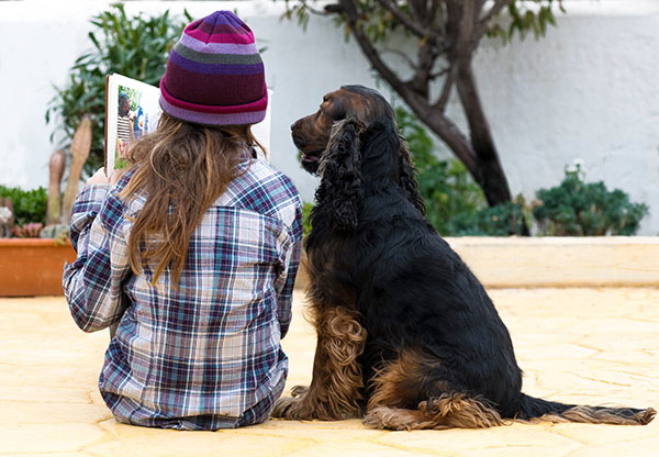 Child reading a book with a dog